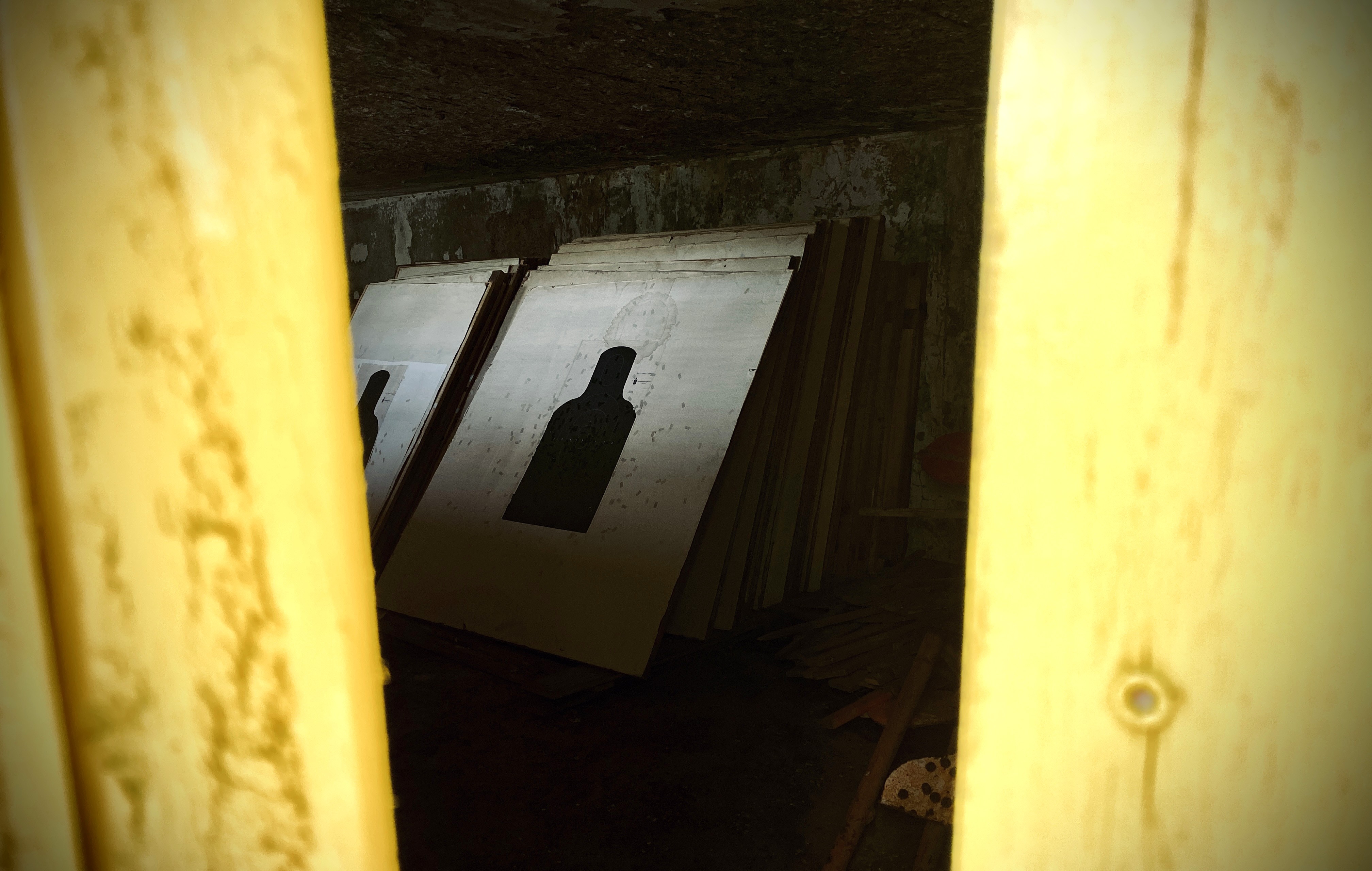Bullet-riddled silhouette targets stored in the dim belly of the berm at Camp Gruber
