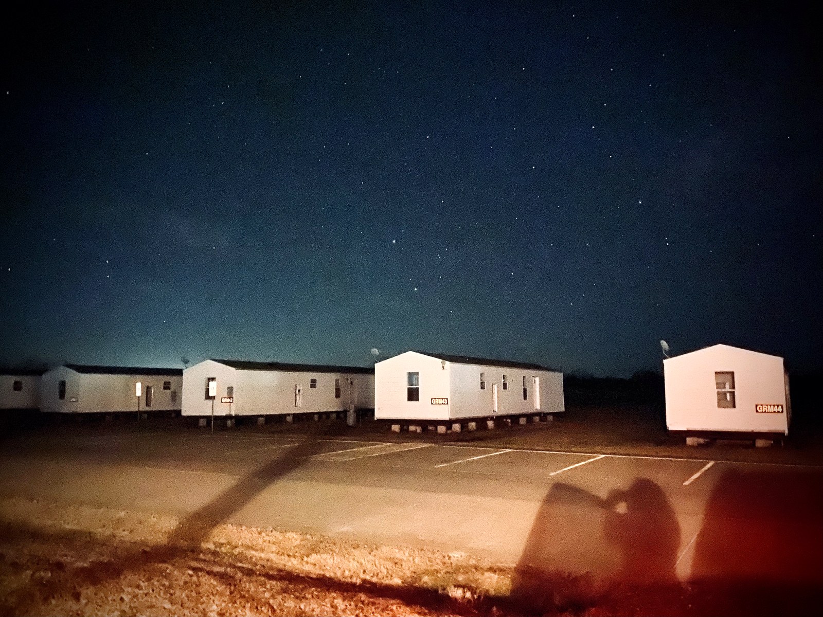 Rows of pale barracks at Camp Gruber standing under a star-filled night sky